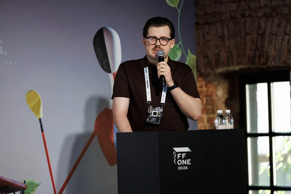 A close-up of Georgii Kumurzhi holding a microphone at the OFFZONE 2026 lectern