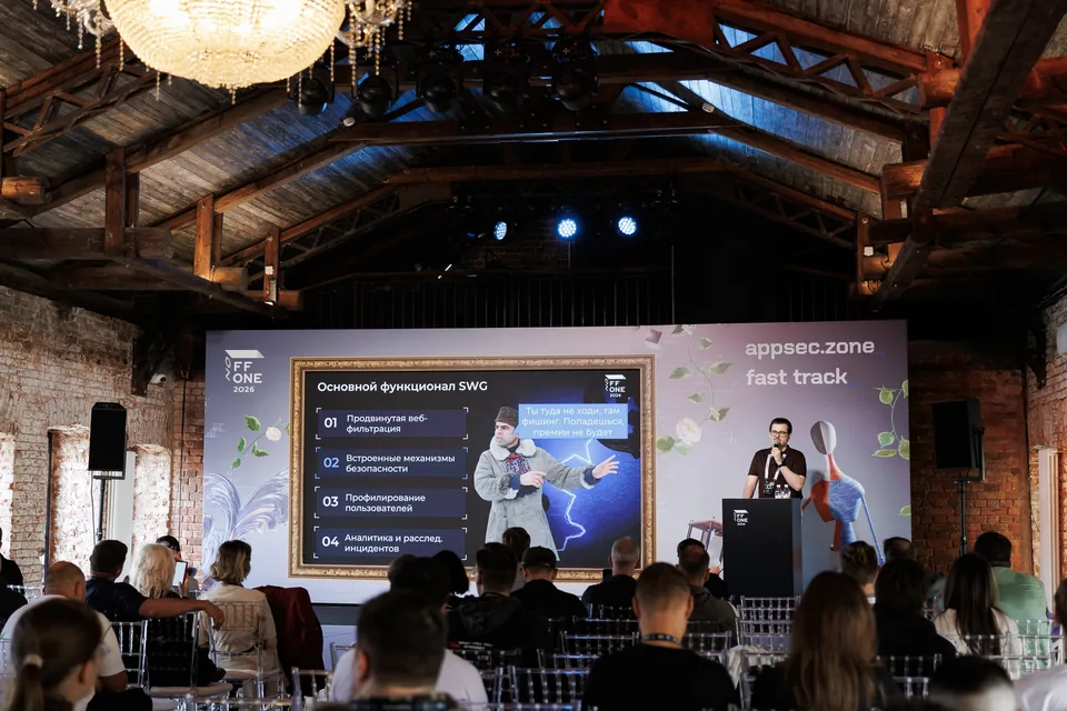 A wide view of the audience and stage with a slide about SWG functionality at OFFZONE 2026